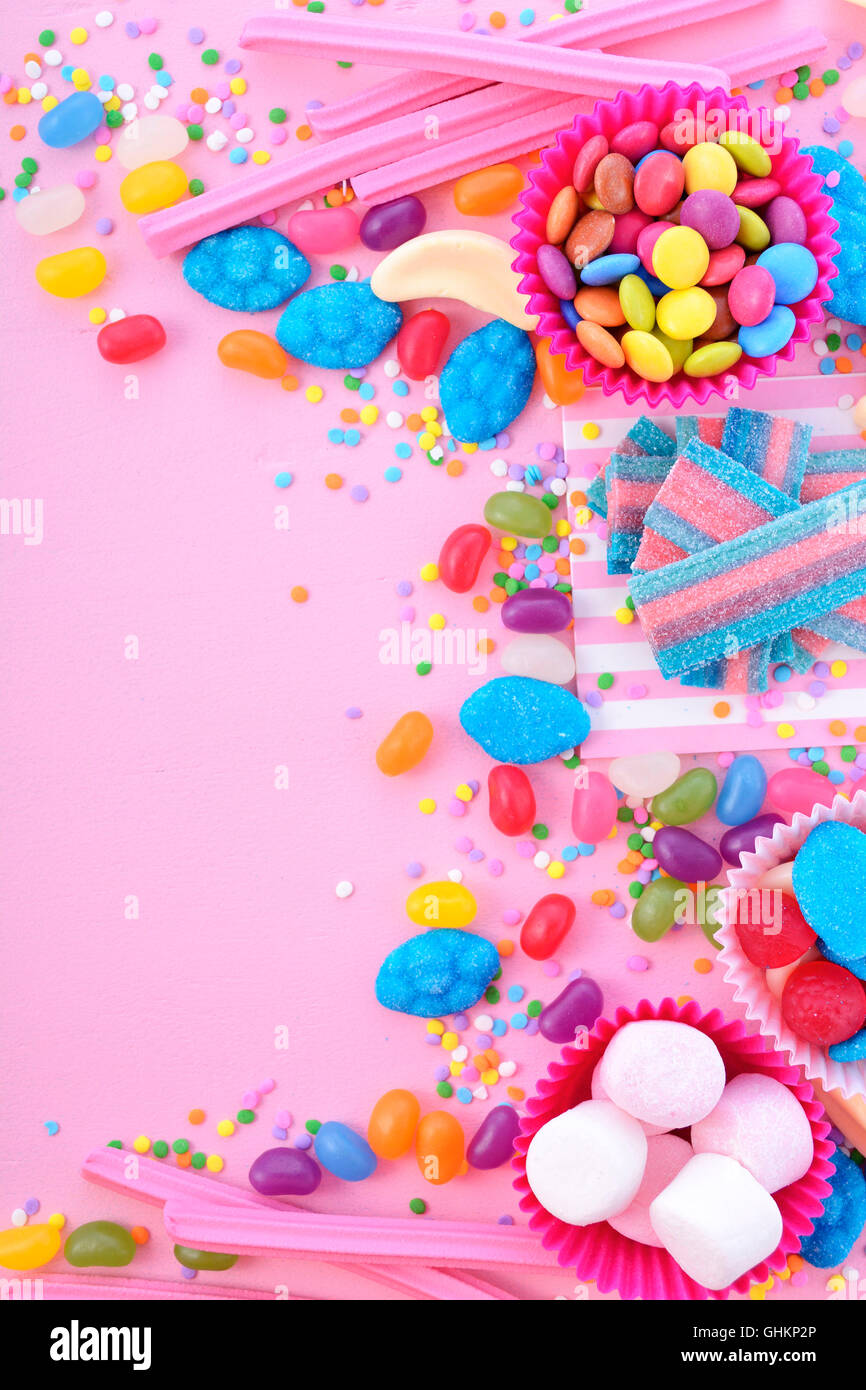 Hintergrund mit dekorierten Grenzen von leuchtend bunten Süßigkeiten in rosa Holztisch für Halloween Trick behandeln oder Kinder Geburtstag Stockfoto