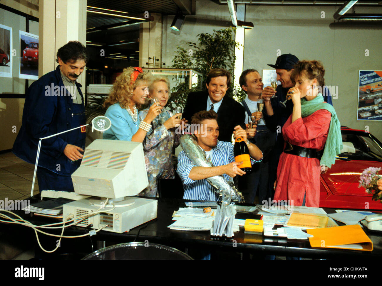 Folge: Das Jubiläum Peter Hut Seine Gesellenprüfung Bestanden. Das FRITZE-Team Feiert Spontan Den Erfolg in Konrads Autosalon. Foto Vlnr.: Ali (SUAVI EREN), Loretta (KARIN DAVID), Frau Kewenig (EDITH HANCKE), Konrad (SIGMAR SOLBACH), Peter Fritze (MARKUS HOFFMANN), Kalle (RÜDIGER WANDEL), Heinz (CLAUDIUS FREYER), Cordula (KAY HELMICH). Regie: Rolf von Sydow aka. 16. Das Jubiläum Stockfoto