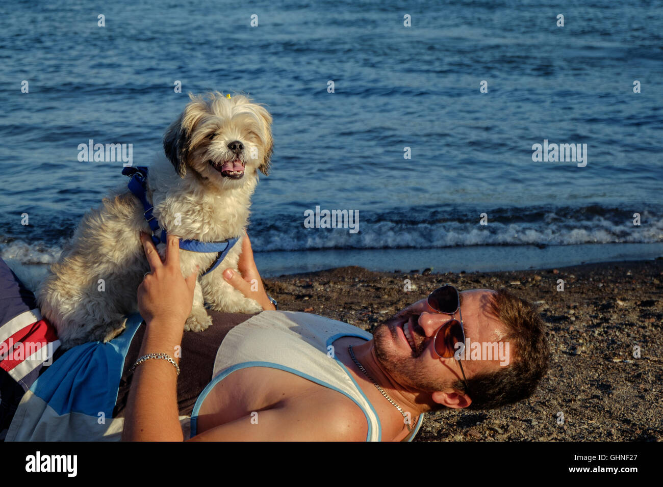 Ein Mann und ein Hund an einem Strand umarmt Stockfoto