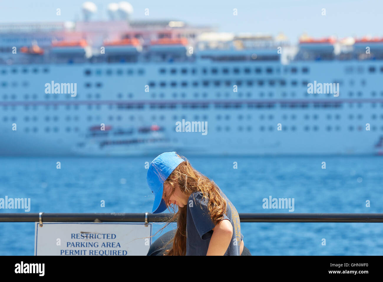 Junge Mädchen stehen von der Waterfront im Avalon, Catalina Island. Der Carnival Inspiration hinter verwischt. Stockfoto