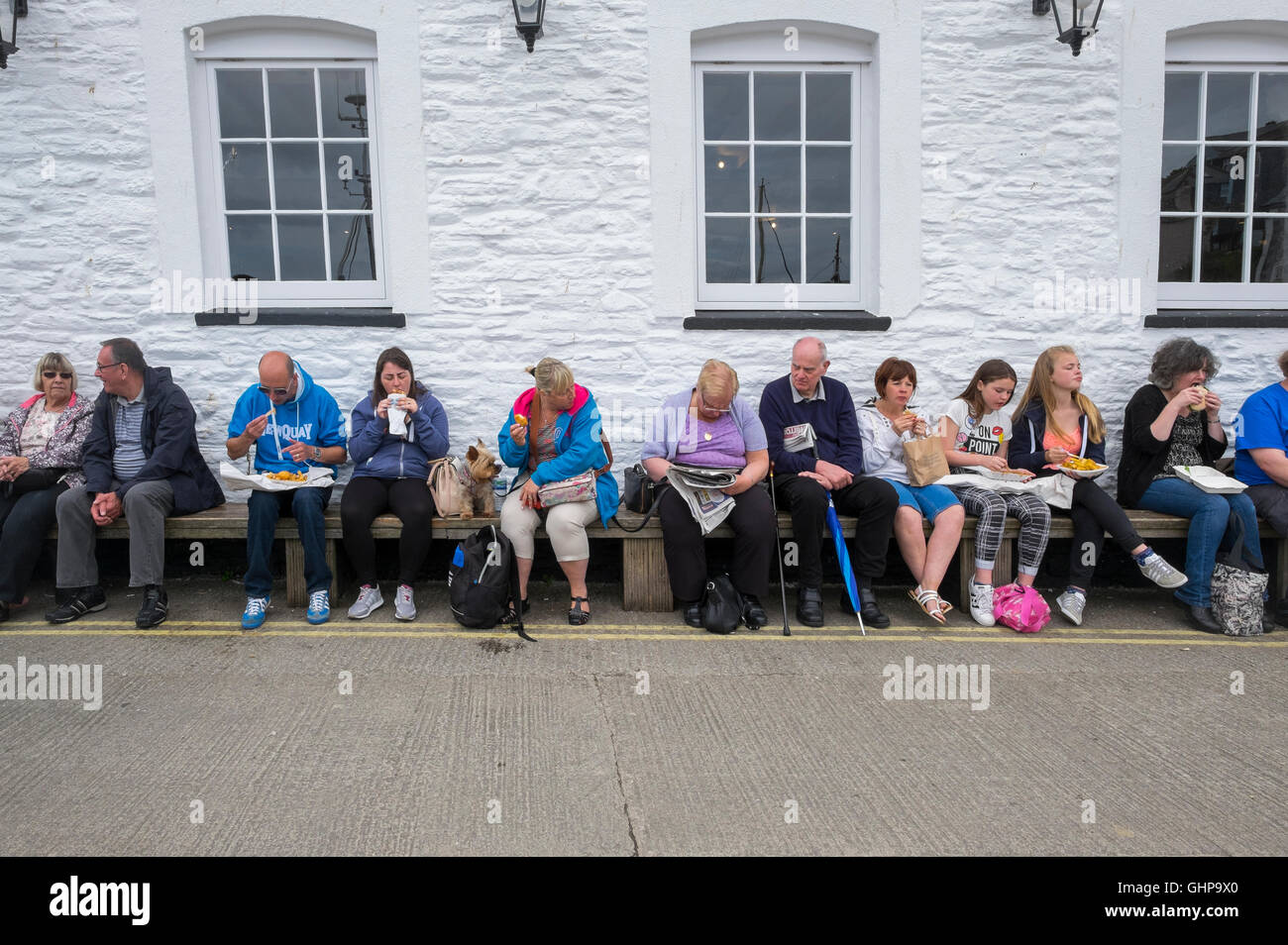 Eine Reihe von Menschen, die Essen Fish &amp; Chips bei Mevagissey, Cornwall, England, UK Stockfoto