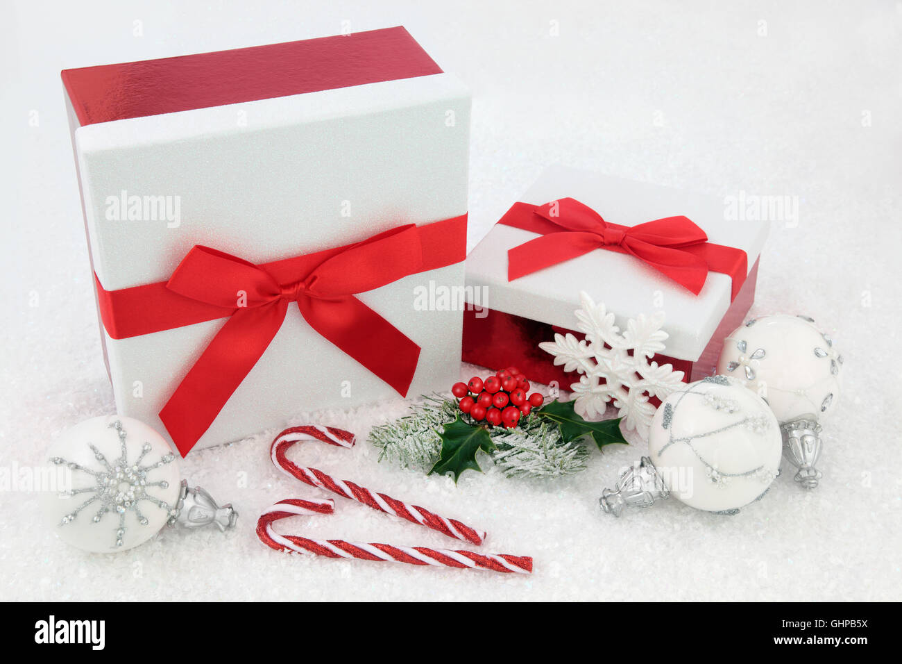 Weihnachten Glitzer-Geschenk-Boxen mit roten Schleifen, Zuckerstangen, Holly, Tanne und weißen Schneeflocke Christbaumkugel Dekorationen auf Schnee Hintergrund. Stockfoto