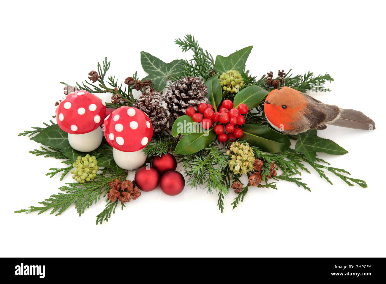 Weihnachten Deko Display mit Robin, roten Kugeln und Fliegenpilz Pilz Dekorationen mit Holly, Efeu, Schnee bedeckte Tannenzapfen Stockfoto