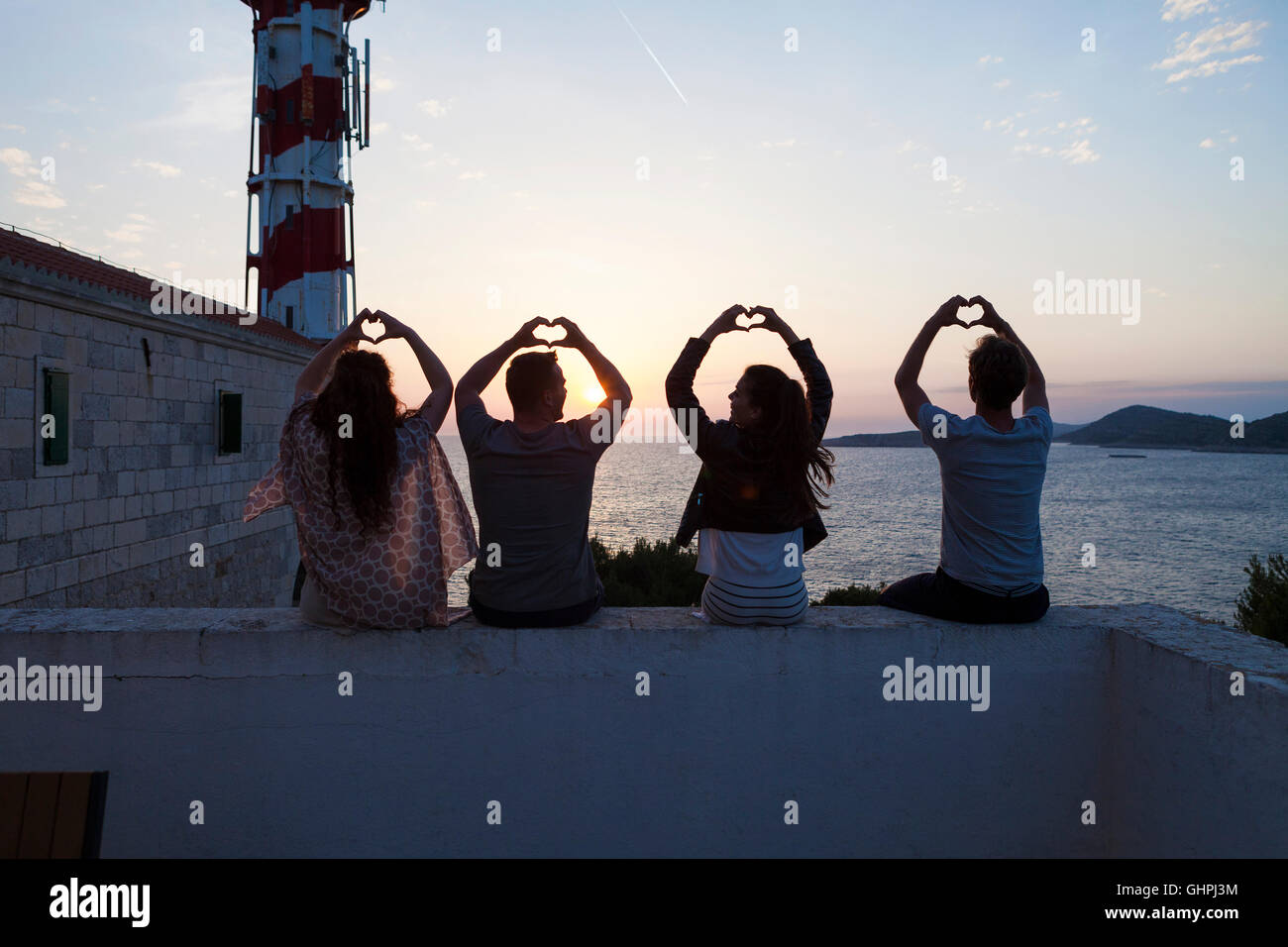 Junge Menschen, die Herzformen mit Händen am Meer Stockfoto