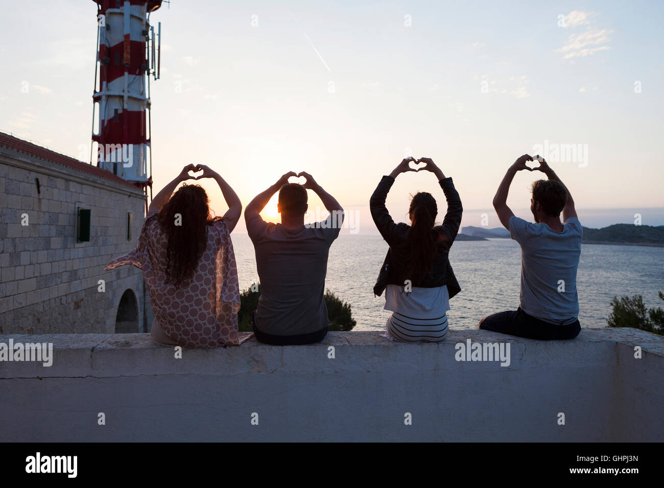 Junge Menschen, die Herzformen mit Händen am Meer Stockfoto