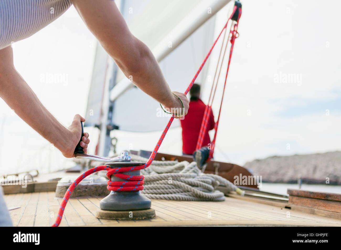 Mann, die Wicklung Seil mit Seilwinde auf Segelboot Stockfoto