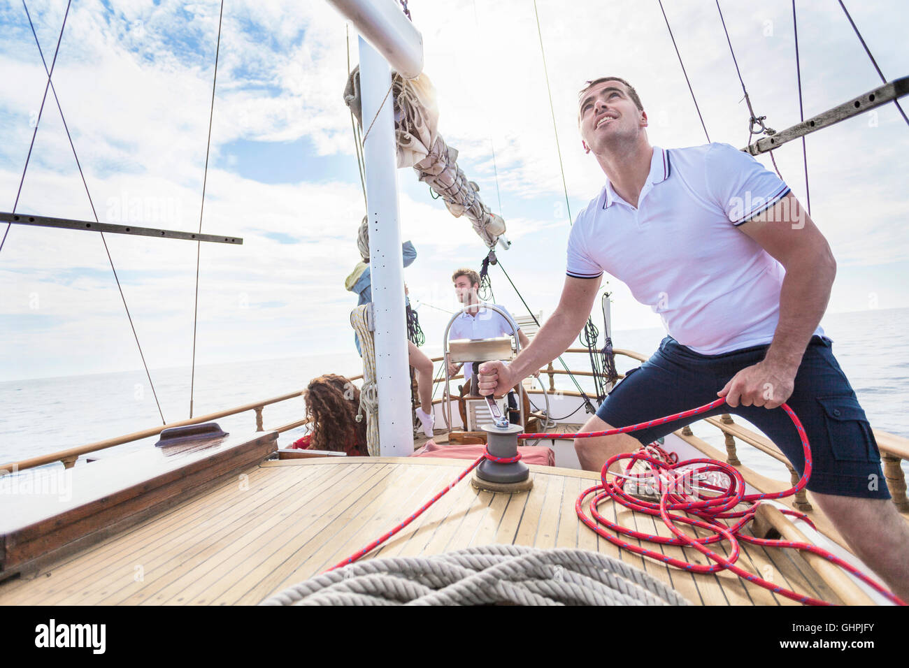 Mann, die Wicklung Seil mit Seilwinde auf Segelboot Stockfoto