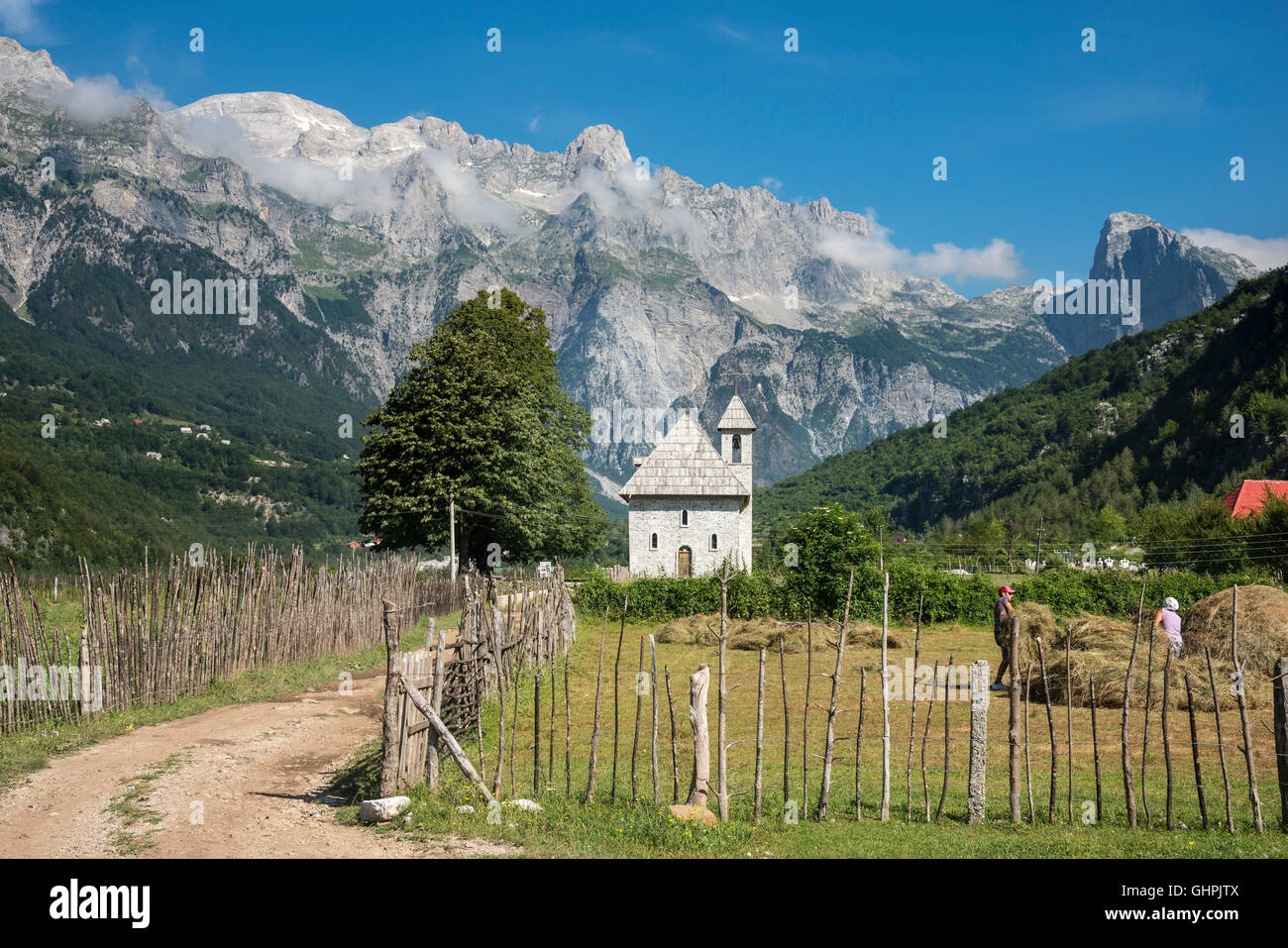 Blick über das Dorf Theth mit der Schindel überdachte Kirche und die albanischen Alpen im Hintergrund, Nordalbanien. Stockfoto