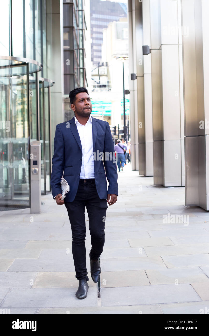 Indische Geschäftsmann zu Fuß mit einer Zeitung Stockfoto