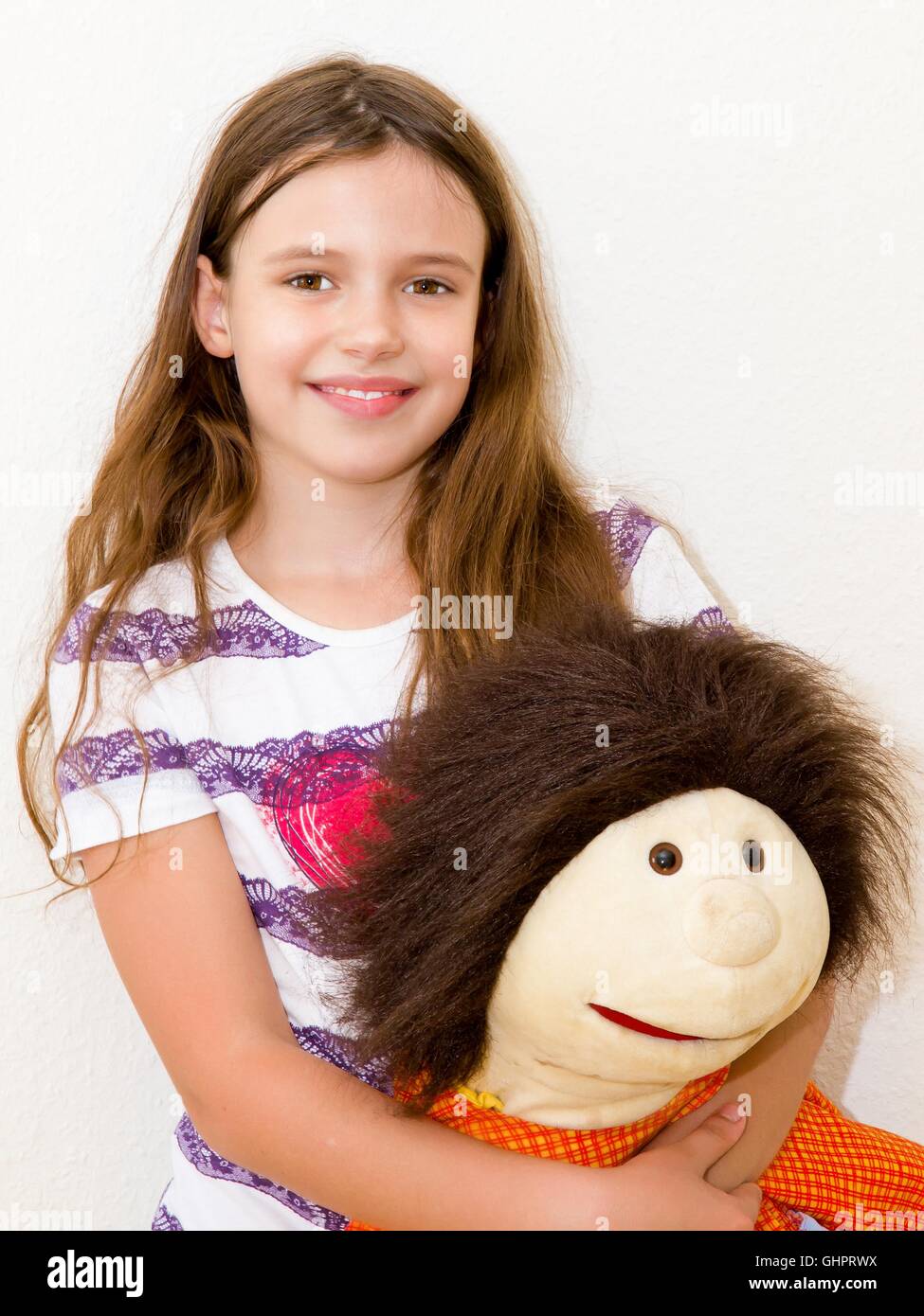 Kleines, fröhliches Mädchen mit Puppe Stockfoto