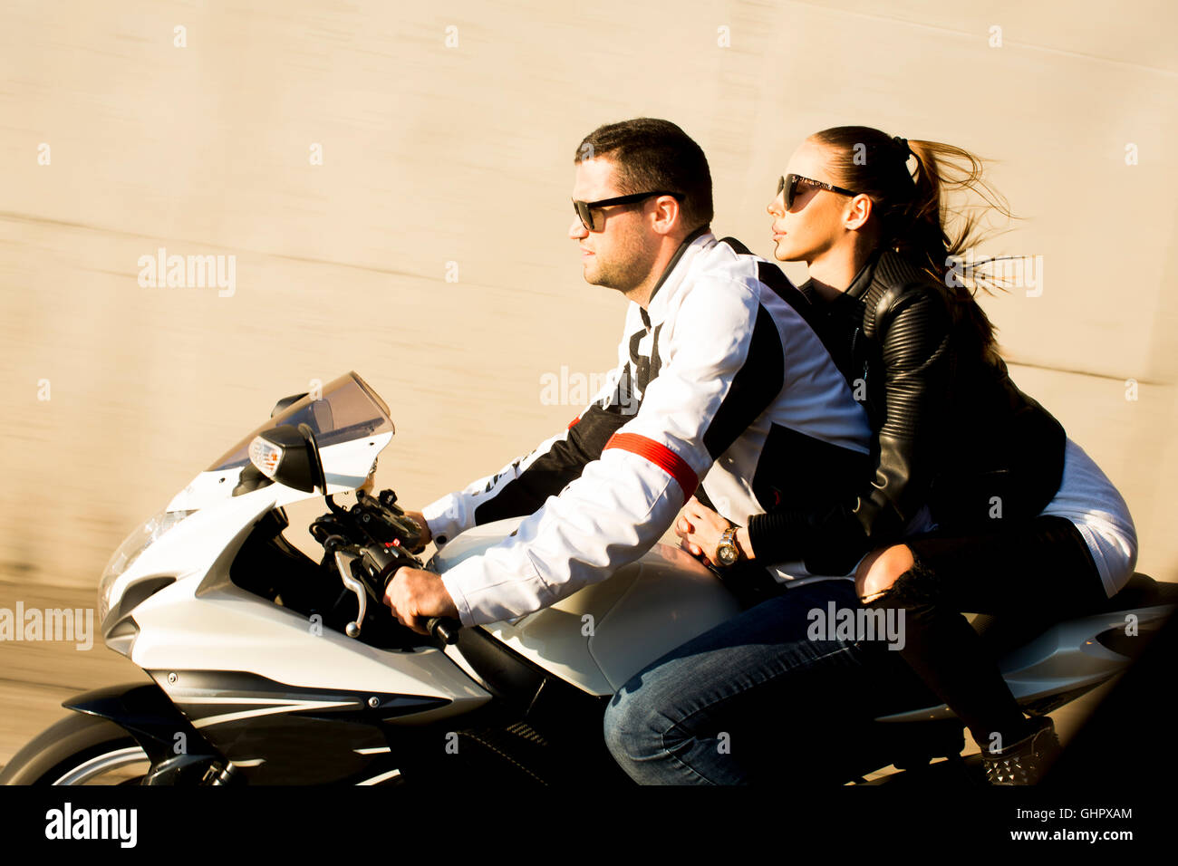 Mann und Frau tragen Lederjacken und stilvolle Sonnenbrille Reiten auf Motorrad Stockfoto