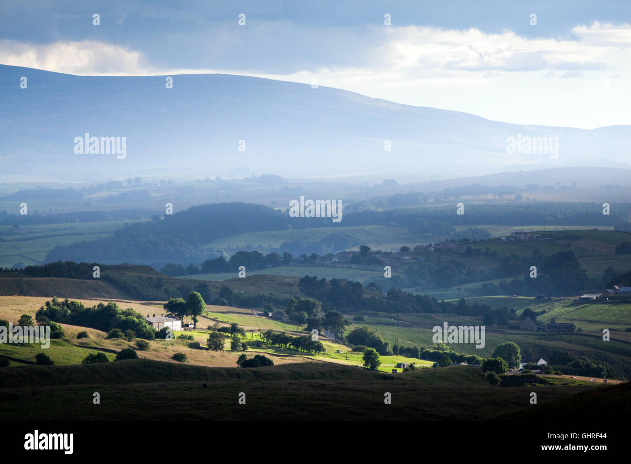 Ein Sonnenstrahl Fang das Bauernhaus und Felder mit Nebel steigt in der Ferne vor der Pennine hills Stockfoto