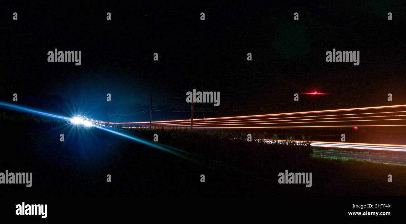 Langzeitbelichtung Nachtaufnahme von einem Lastwagen fahren durch auf einer Straße neben einem Maisfeld bei Nacht. Stockfoto