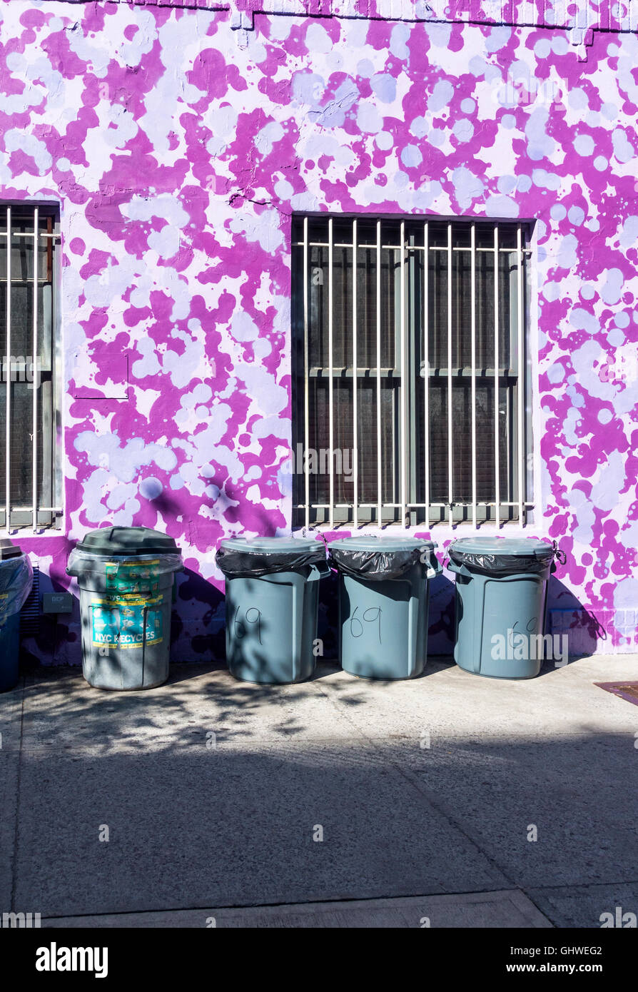 Mülltonnen vor einem bunt bemalten Gebäude im East Village in New York City Stockfoto
