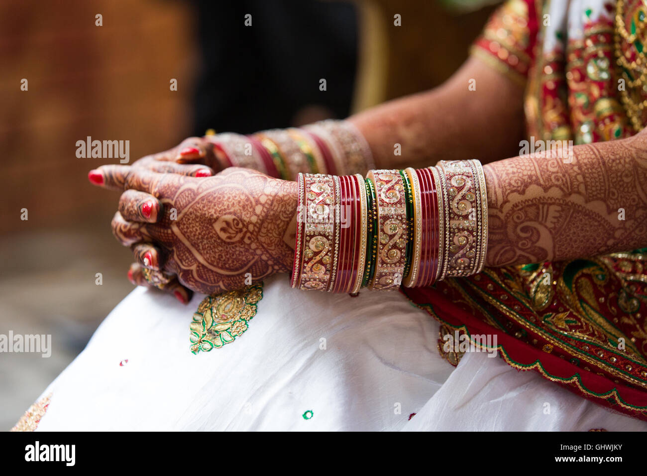 Indische Braut mit Armreifen, Tattoos mit Waffen auf den Knien sitzend Stockfoto