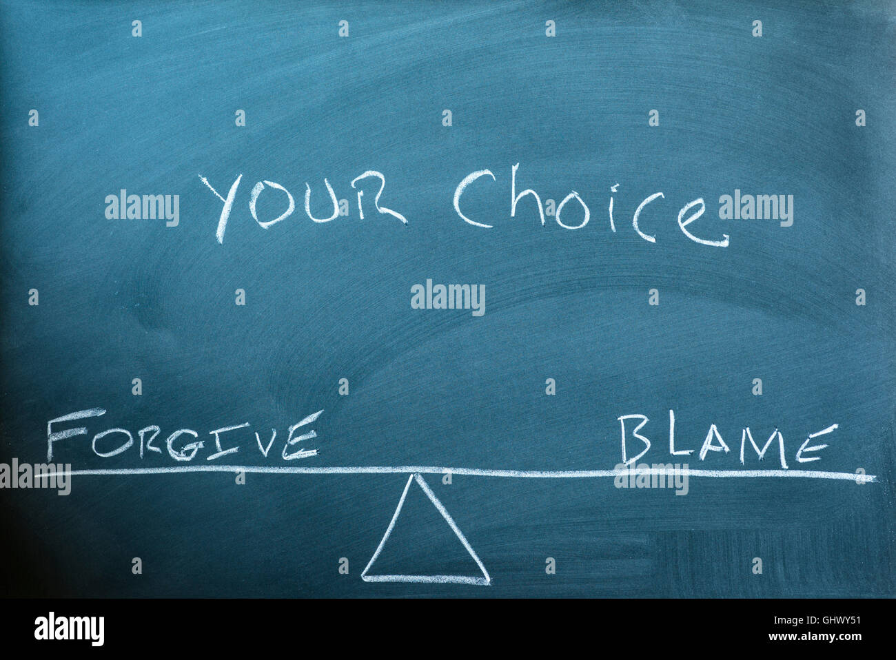 die Worte vergeben und die Schuld auf eine Waage im Gleichgewicht auf einer Tafel geschrieben. Stockfoto