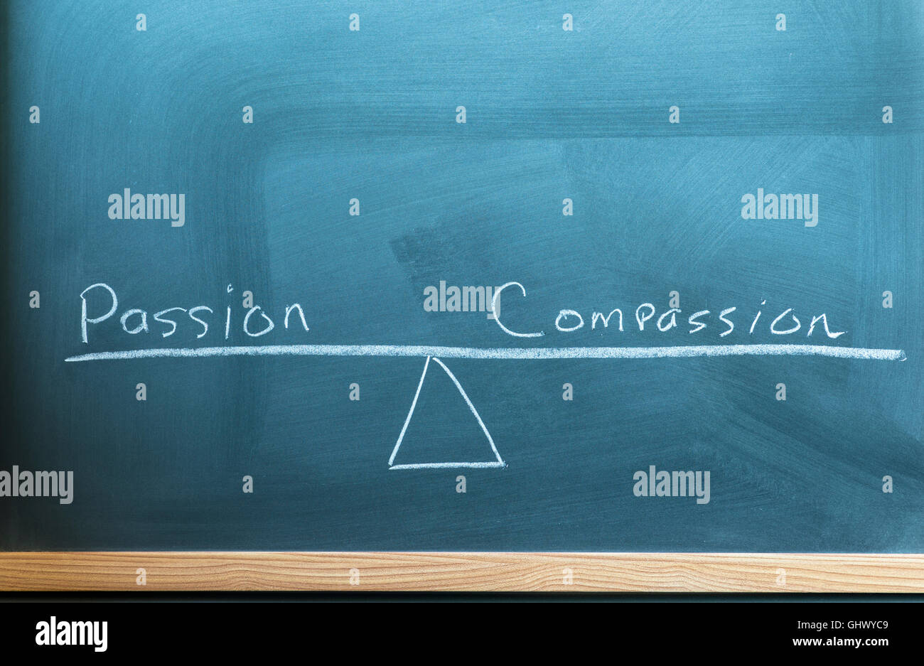 die Worte Leidenschaft und Mitgefühl auf einer Skala im Gleichgewicht auf einer Tafel geschrieben. Stockfoto
