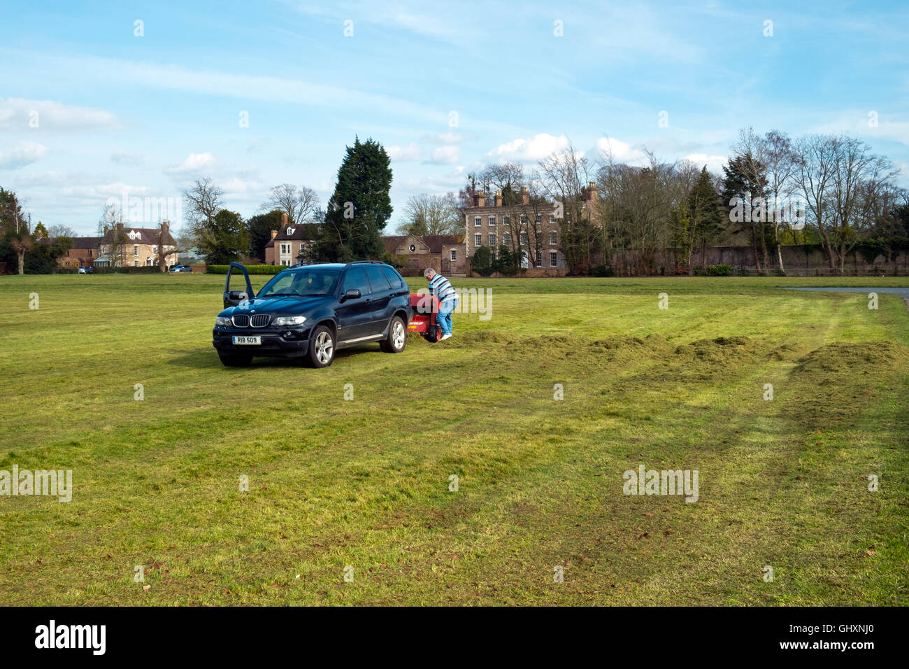 Ein Mähwerk mit einem BMW Auto abschleppen. Mähen der Cricket-Platz am Frampton auf Severn, Gloucestershire, UK Stockfoto