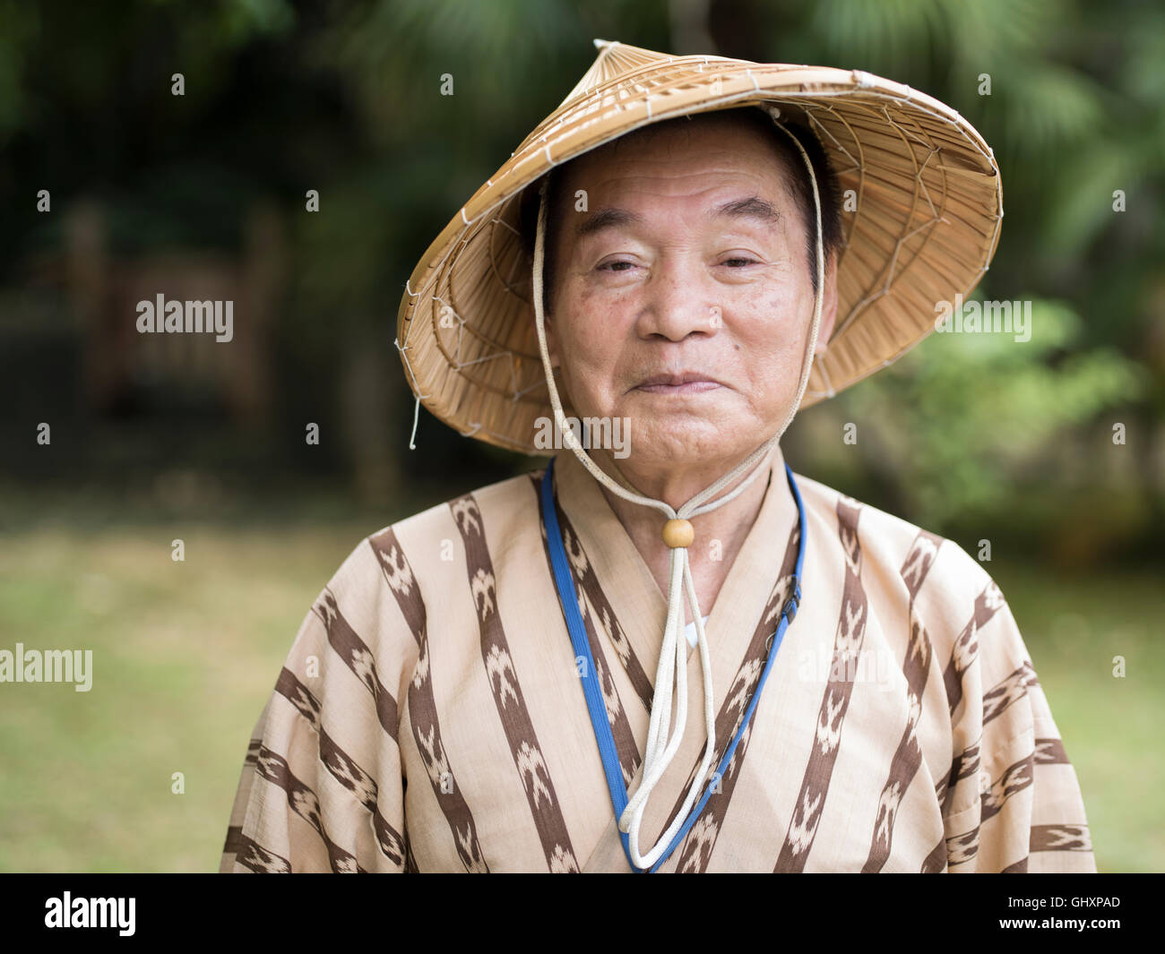 Okinawan Senior in seinem 70 trägt traditionelle Bashofu Stil Kimono und Stroh Hut. Okinawa ist eine Langlebigkeit blaue Zone. Stockfoto