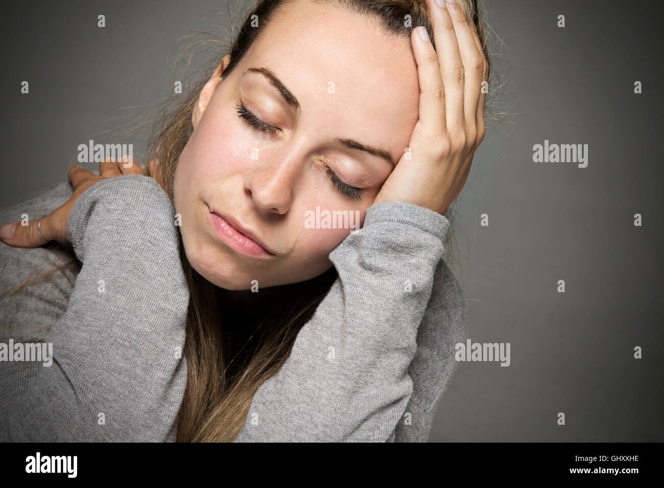 Traurige junge Frau mit Augen geschlossen Tränen rannen aufgedeckte nahe Blatt am Kopf Traurigkeit Konzept Stockfoto
