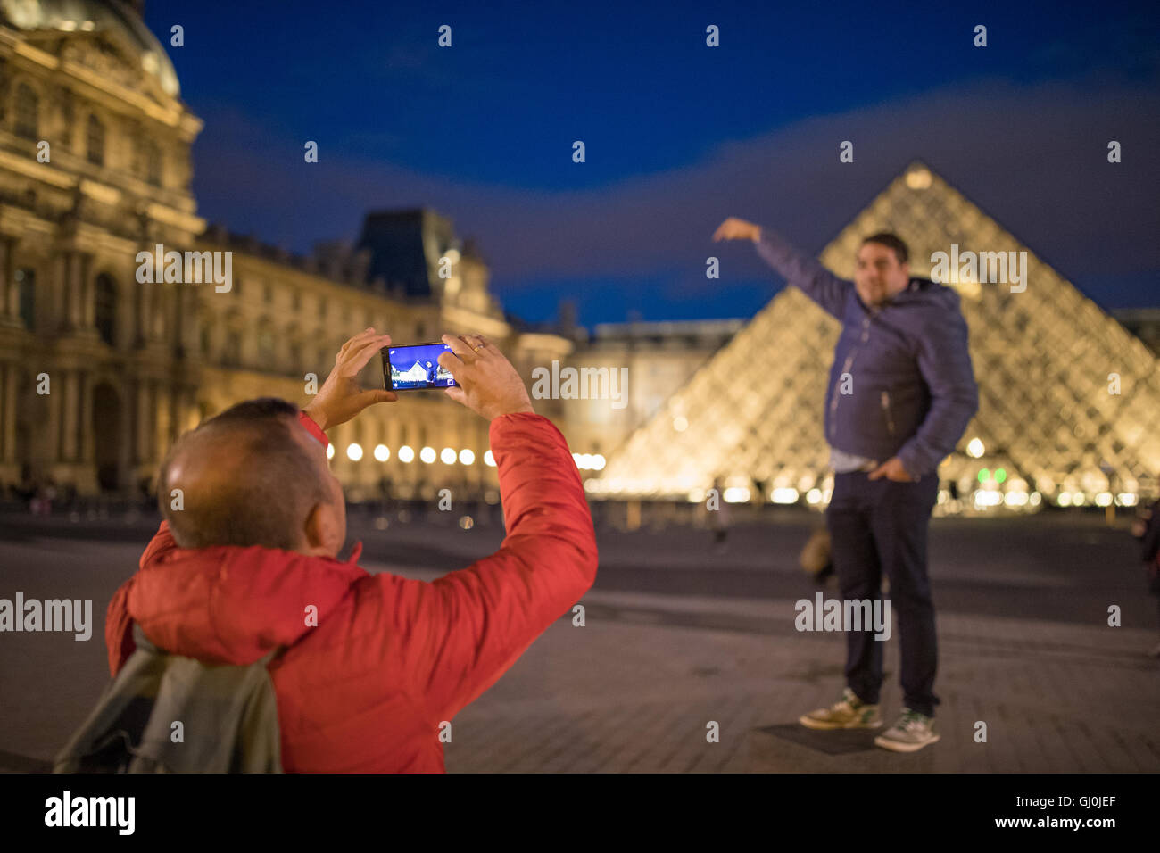 Touristen fotografieren am Palais du Louvre in der Abenddämmerung, Paris, Frankreich Stockfoto