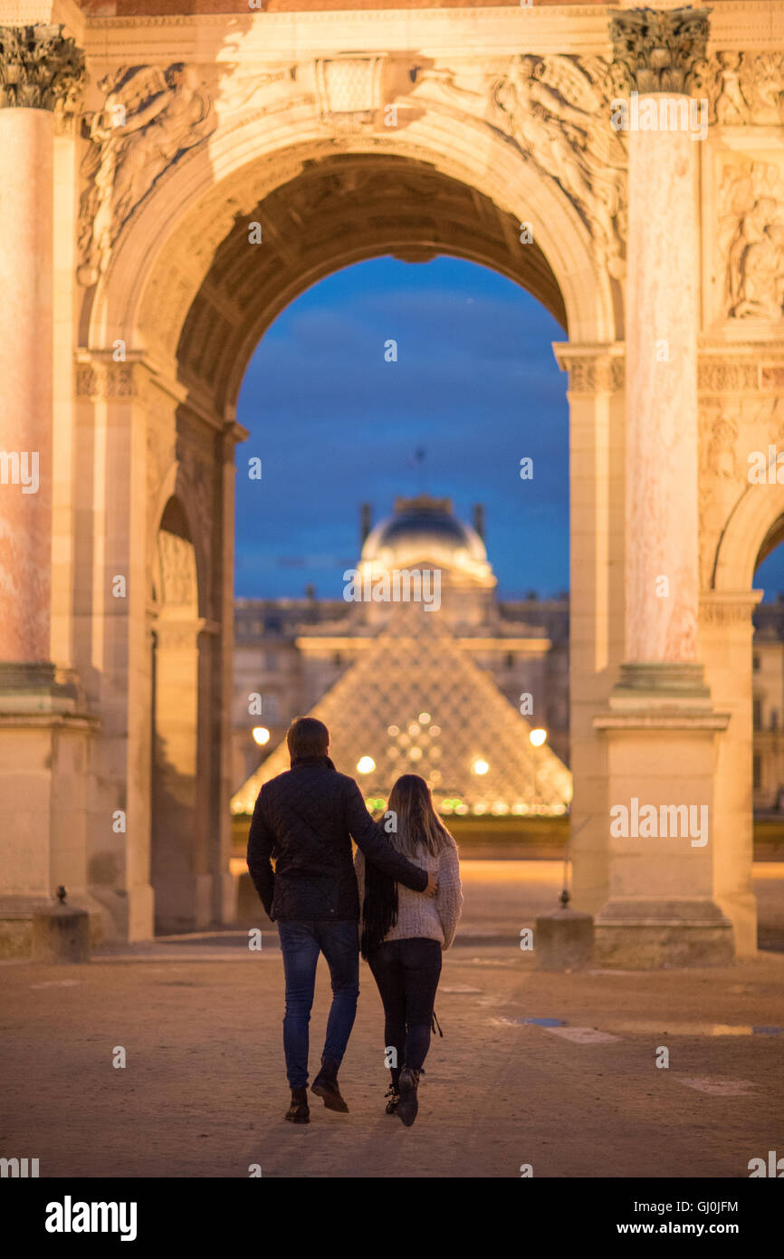 ein paar am Arc de Triomphe du Carrousel & Palais du Louvre in der Abenddämmerung, Paris, Frankreich Stockfoto