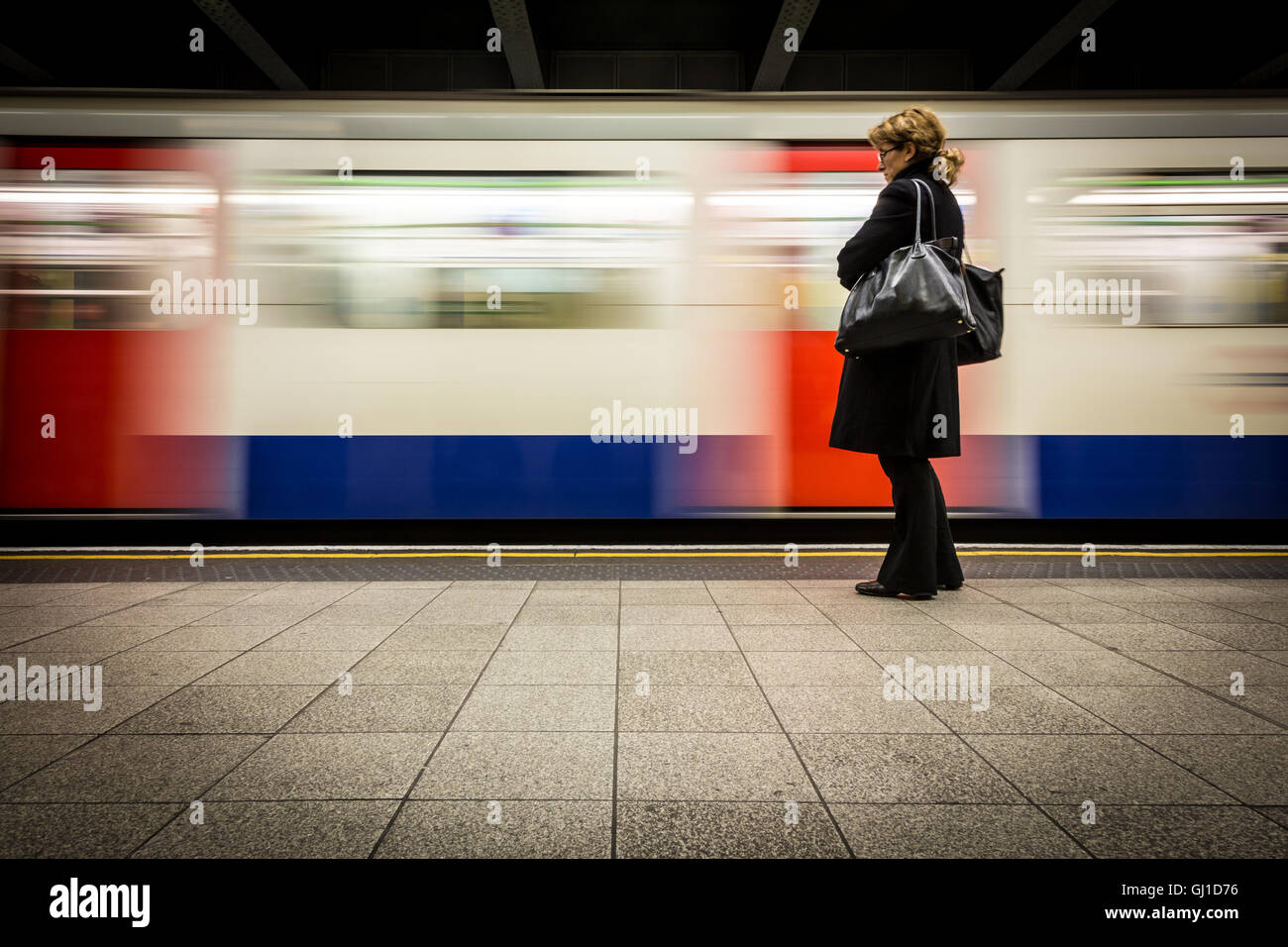 Eine Frau steht auf einer u-Bahn-Plattform als ein Zug die Station betritt Stockfoto