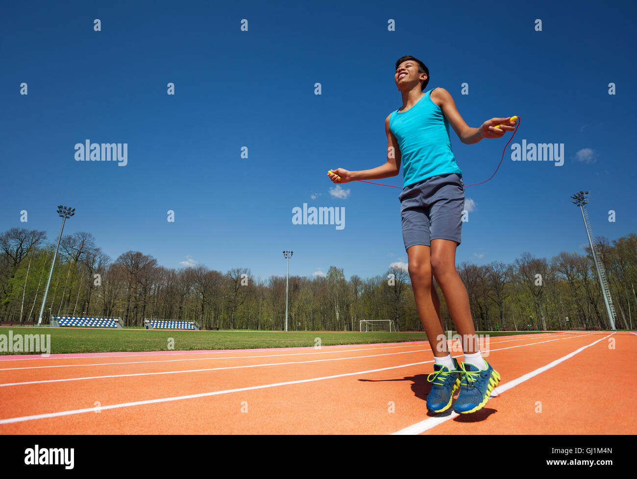 Lächelnde Teenager Athlet Springseil außerhalb Stockfoto