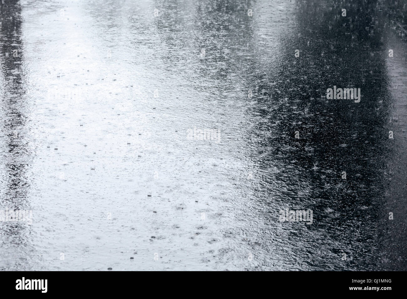nassen Bürgersteig mit Regentropfen in einer Pfütze und Reflexionen Stockfoto