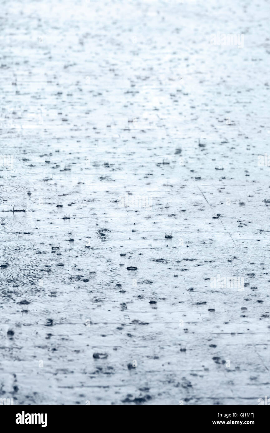 Kopfsteinpflaster mit Pfütze und Regentropfen bei starkem Regen Stockfoto