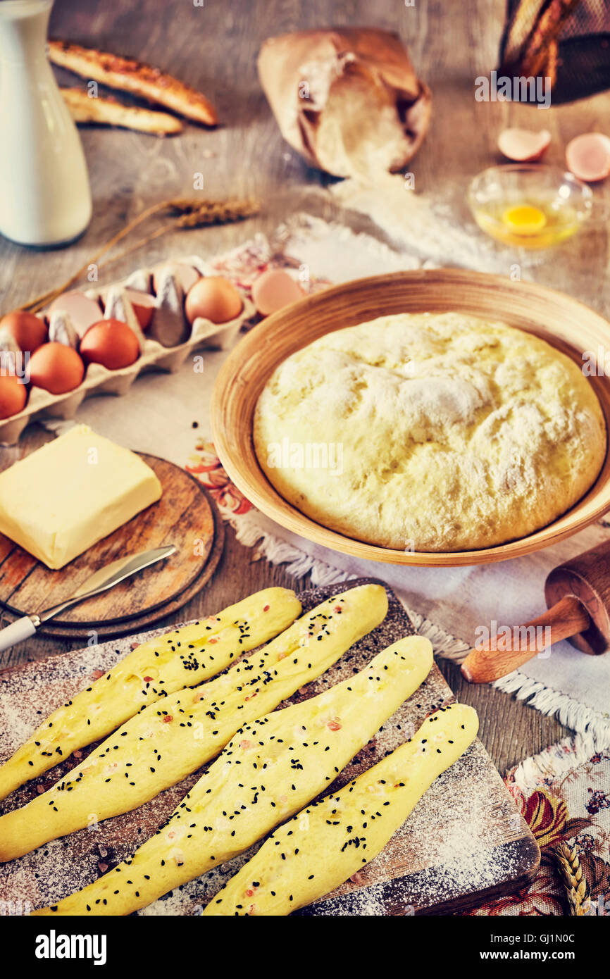 Vintage getönten Brot-Sticks und Hefeteig fertig zum Backen, rustikale Einrichtung auf einem Holztisch. Stockfoto