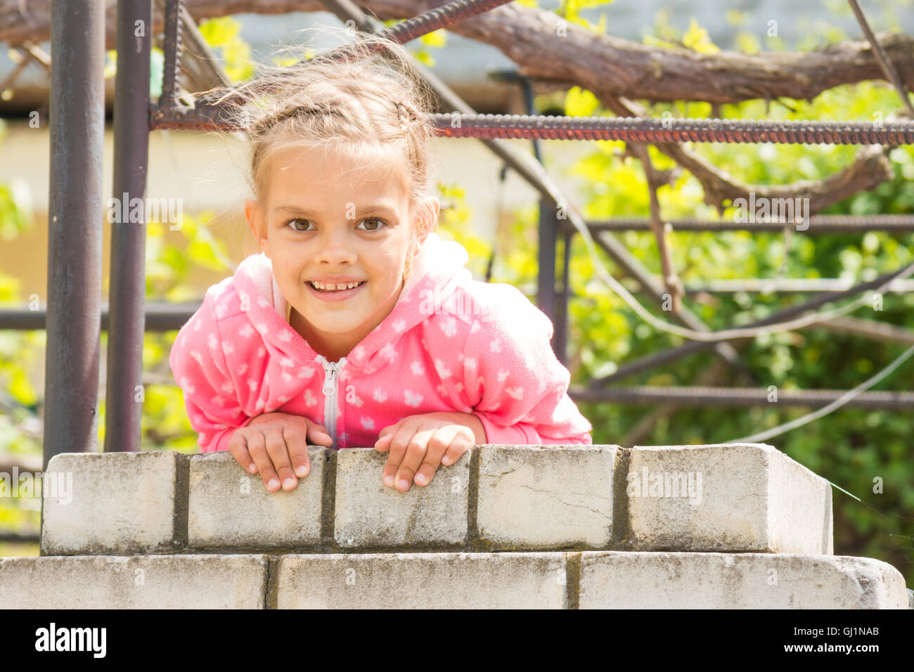 Sieben Jahre glückliches Mädchen hängen an eine Ziegelmauer und sah im Rahmen Stockfoto