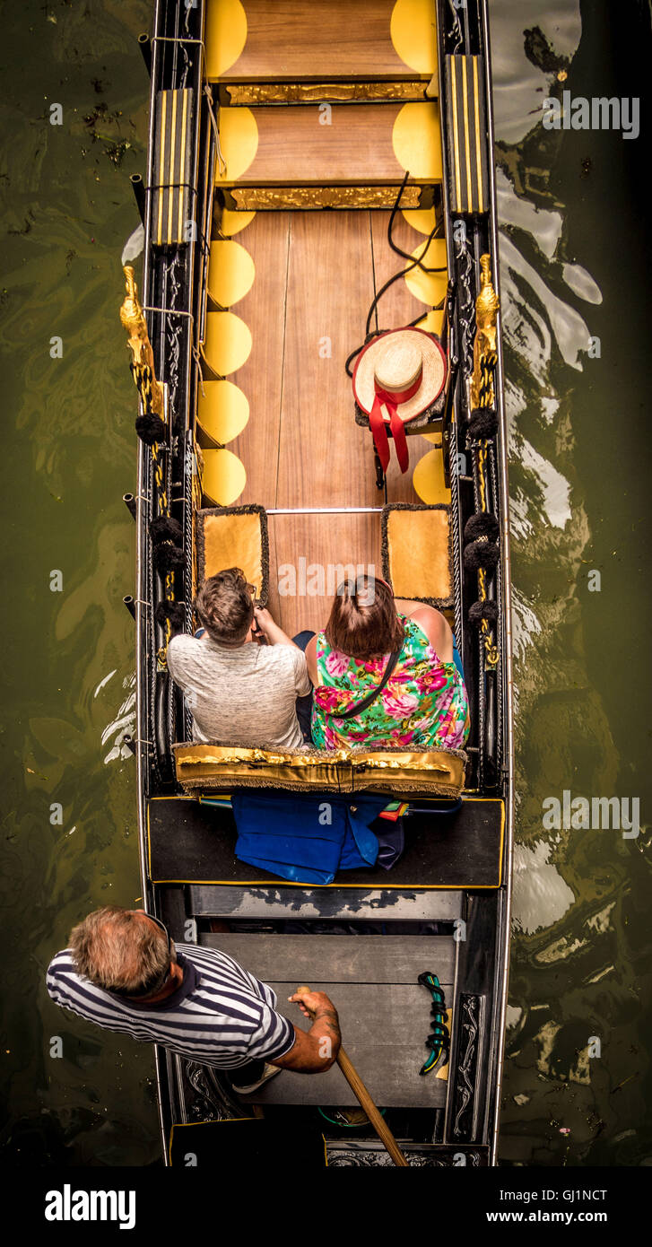 Luftaufnahme eines Paares, das in einer Gondel sitzt und den Gondoliere in einem traditionellen gestreiften Oberteil trägt. Venedig. Italien. Stockfoto