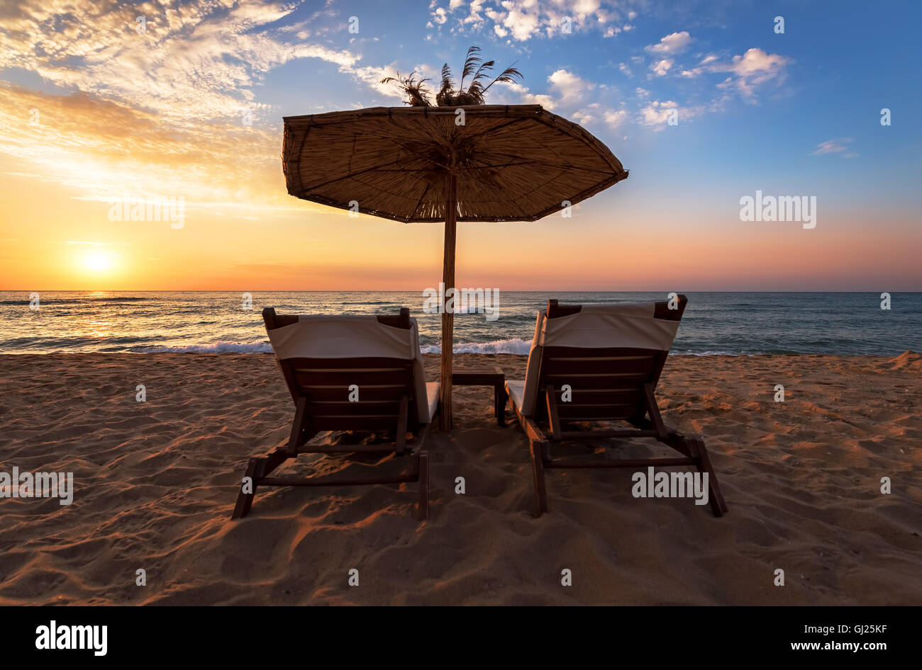 Liegestühle mit Sonnenschirm am Strand. Stockfoto