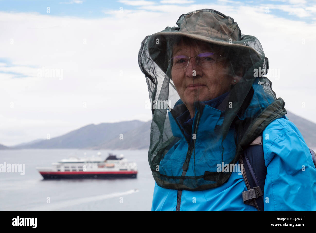 Ein senior weibliche Touristen tragen ein Moskitonetz vor beißende Insekten in einer ländlichen Region an der Küste zu schützen. Qaqortoq, Grönland Stockfoto