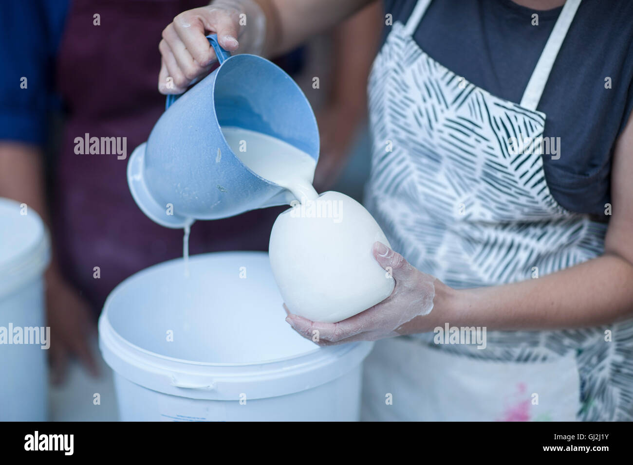 Weibliche Potter strömenden Keramikglasur in Vase in Werkstatt Stockfoto