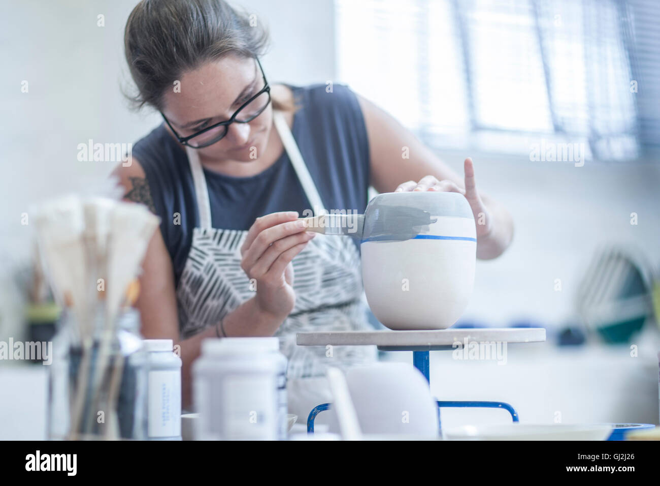 Weibliche Potter Malerei Keramikglasur auf Vase in Werkstatt Stockfoto