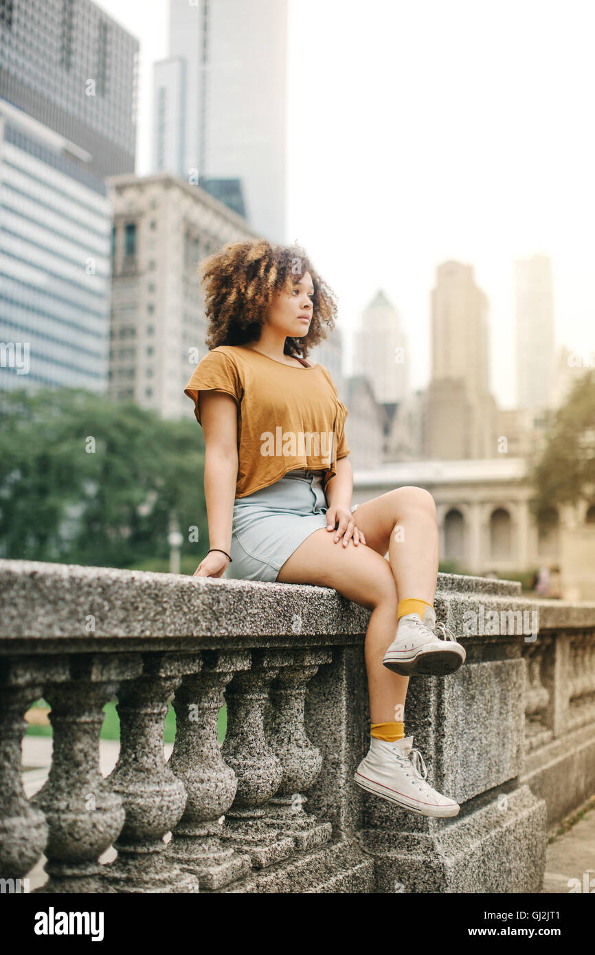 Frau sitzt auf steinernen Balustrade vor der Skyline von Chicago, Illinois Stockfoto