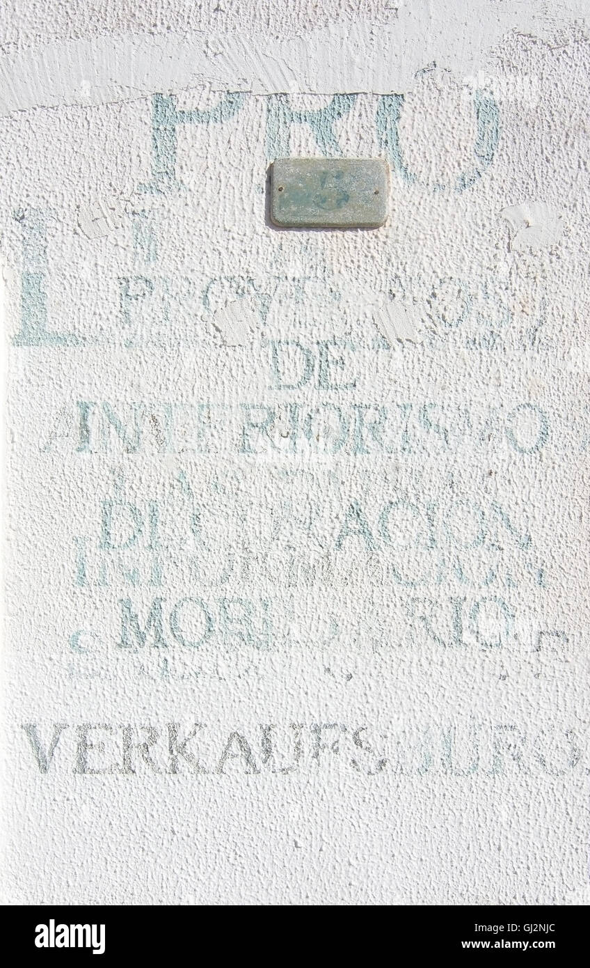 Gedruckte unlegible Wörter in verschiedenen Sprachen auf weißem Putz Wand am 5. August in Port Andratx, Mallorca, Spanien. Stockfoto