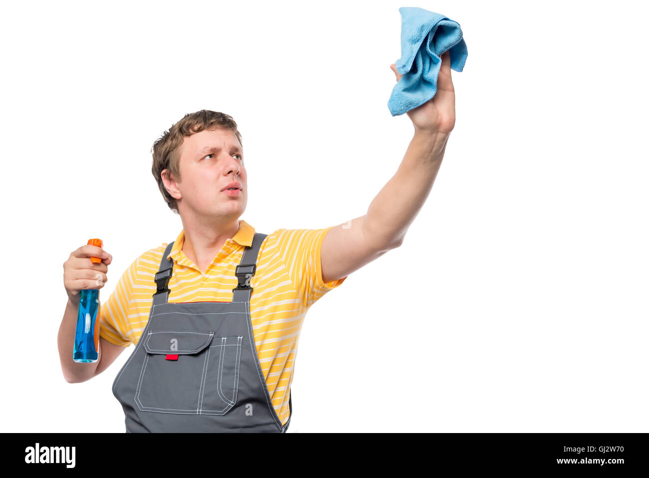 Mann in einem Overall hält eine Flasche mit Spray und Lappen auf weißem Hintergrund Stockfoto