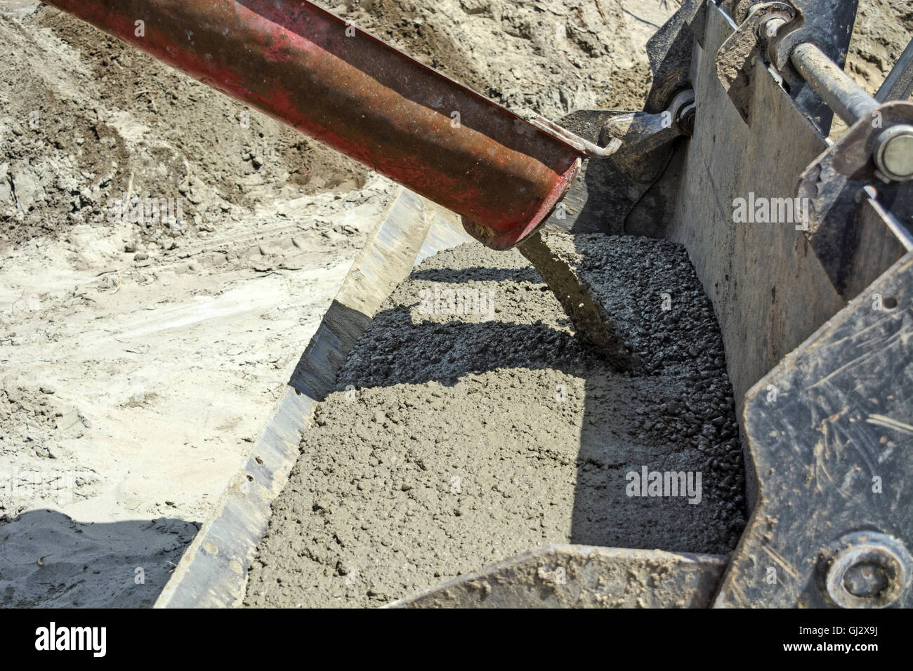 Flüssigen Beton aus dem Mischer Umschalten in einem Löffel Bagger. Stockfoto