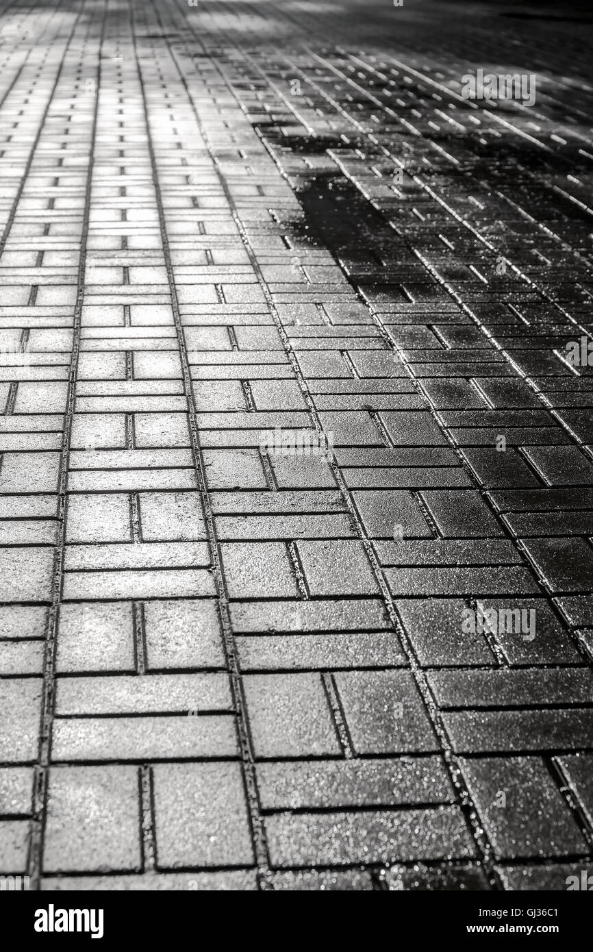 glänzenden nassen Kopfsteinpflaster Bürgersteig städtische Straße Hintergrund Stockfoto