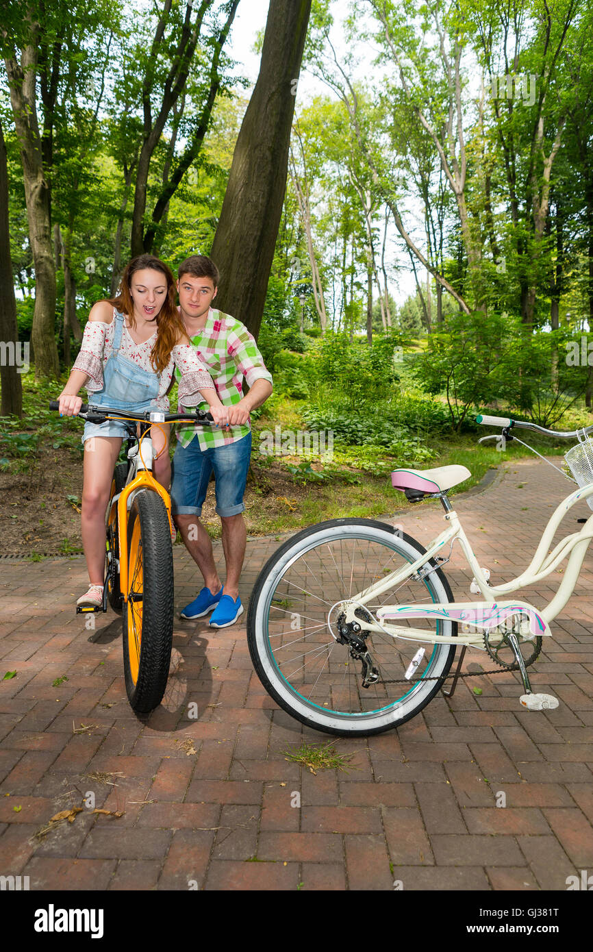 Mann in grün und Rot kariertes Hemd lehrt überrascht junges Mädchen mit dem Fahrrad in einem park Stockfoto