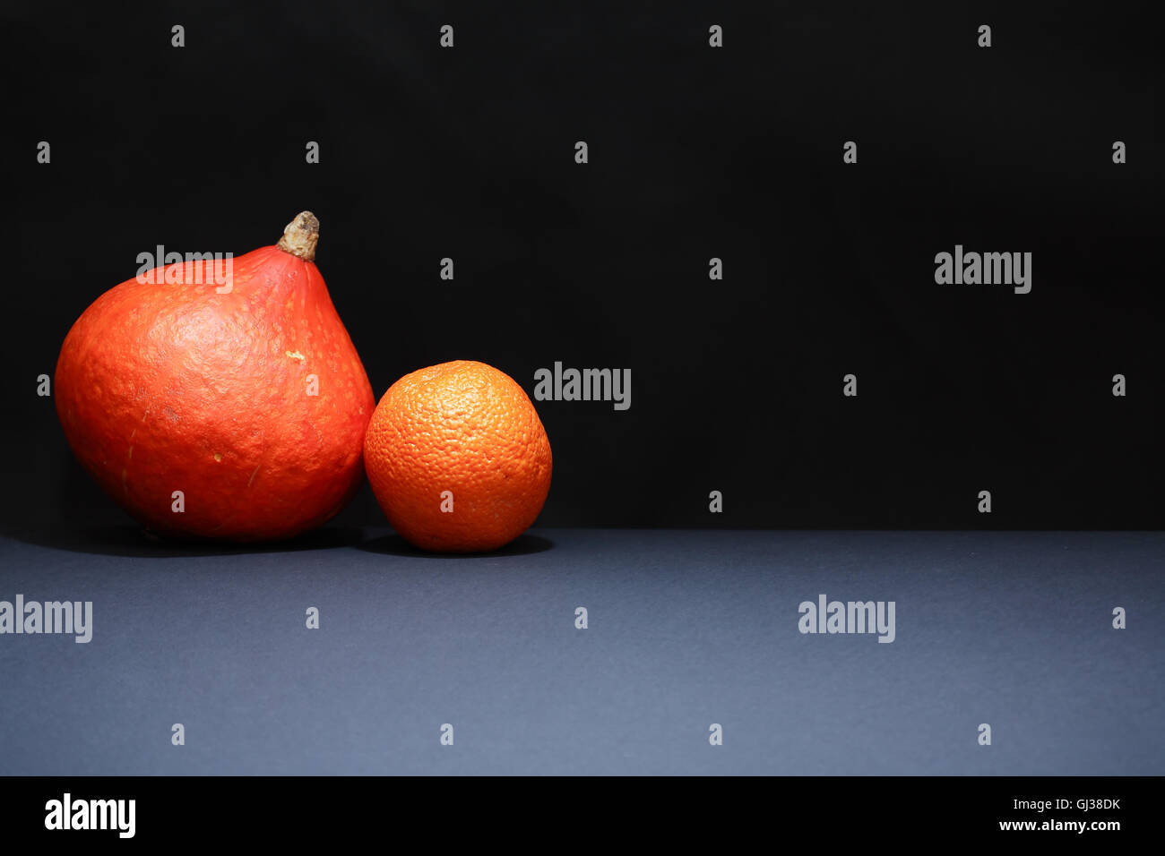 Einen Reifen Kürbis in der Nähe von Orange auf dunklem Hintergrund mit freiem Speicherplatz Stockfoto