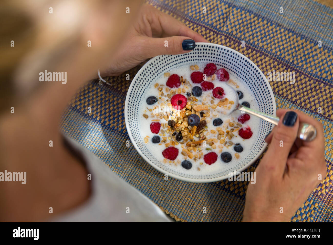 Über Schulter Blick auf Frau Frühstück Getreide und berry Stockfoto