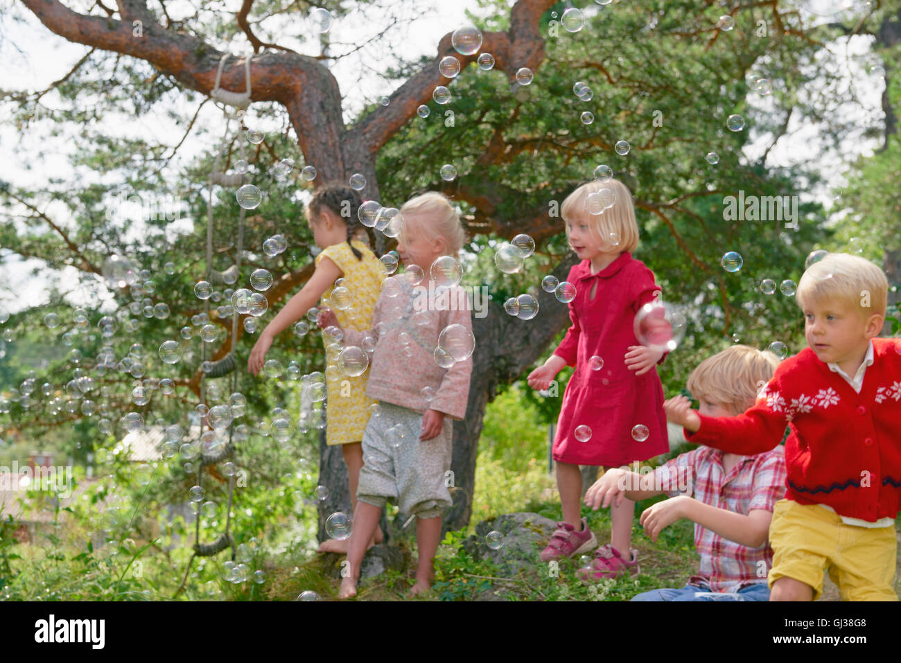 Gruppe von jungen Freunden draußen spielen, Blasen zu erreichen Stockfoto