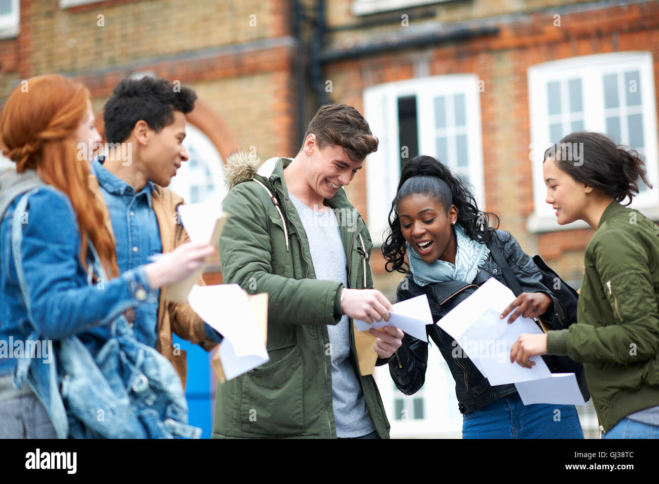 Glückliche junge Erwachsene College-Studenten lesen Prüfungsergebnisse auf dem campus Stockfoto