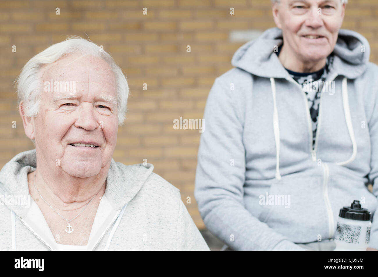 Senioren Freunde Sport Kleidung sitzen zusammen Blick in die Kamera Stockfoto
