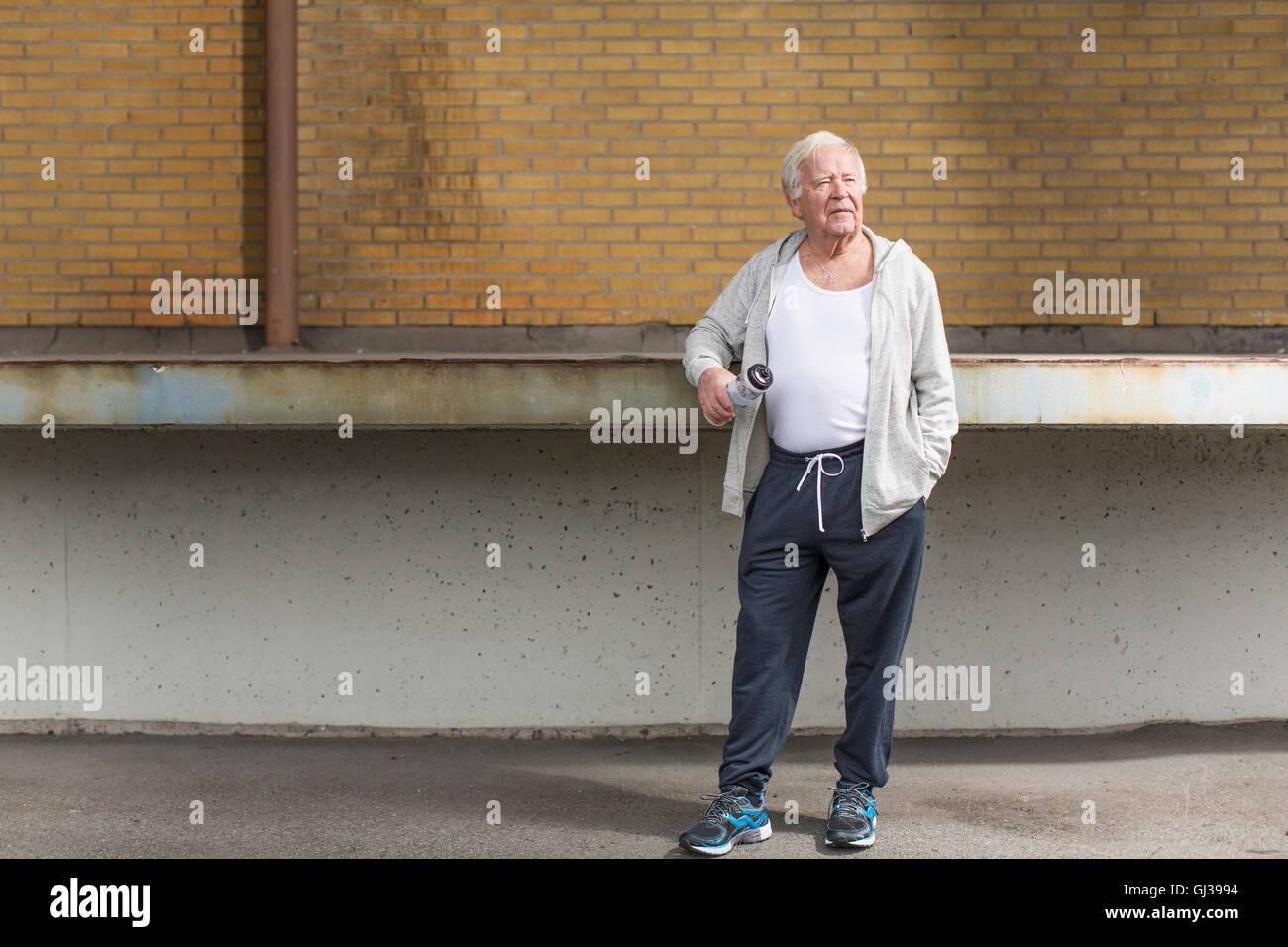 Mann trägt sportliche Kleidung mit Wasserflasche wegschauen Stockfoto