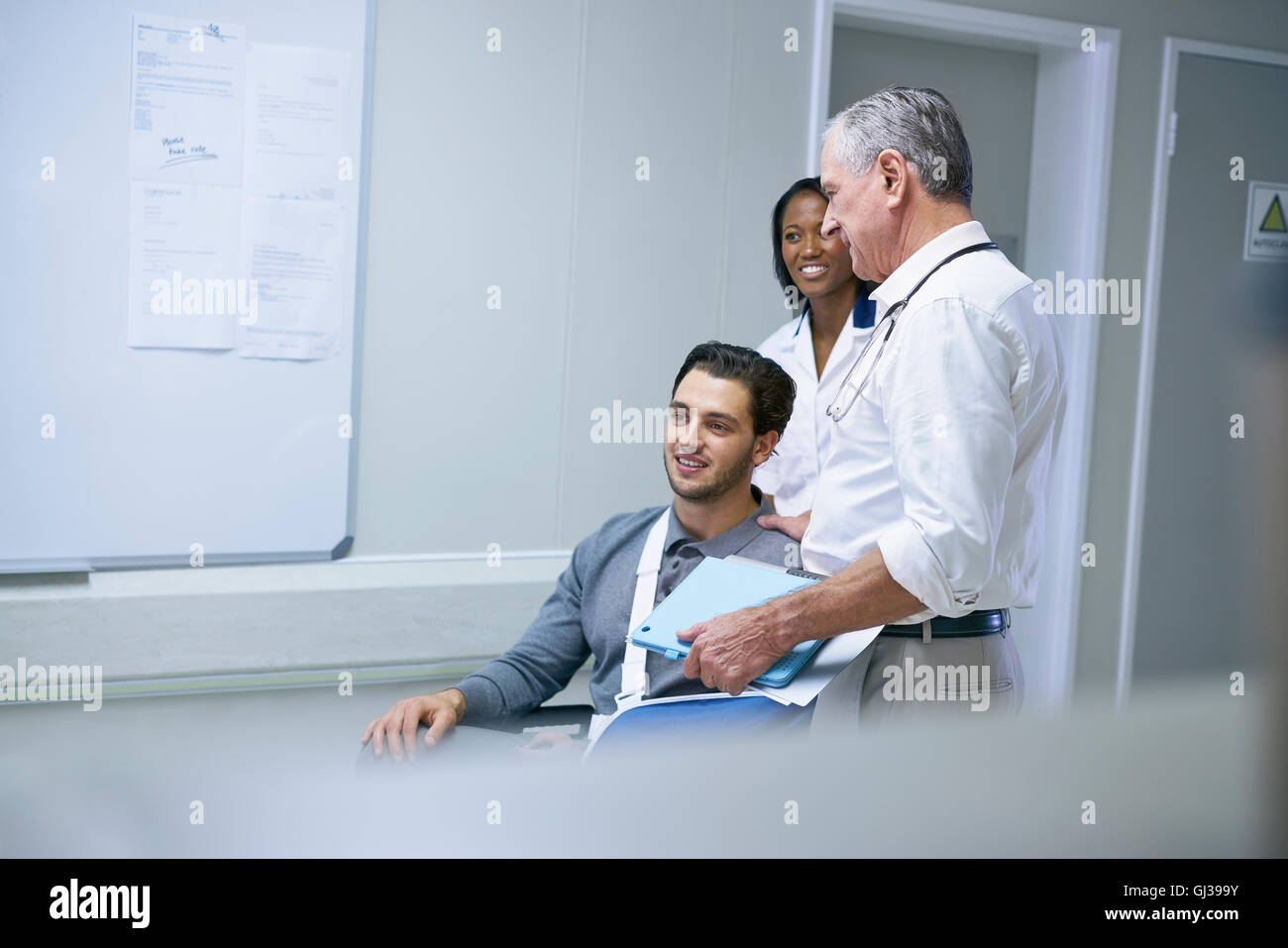 Arzt Beratung mit Mann im Rollstuhl mit Armschlinge Stockfoto